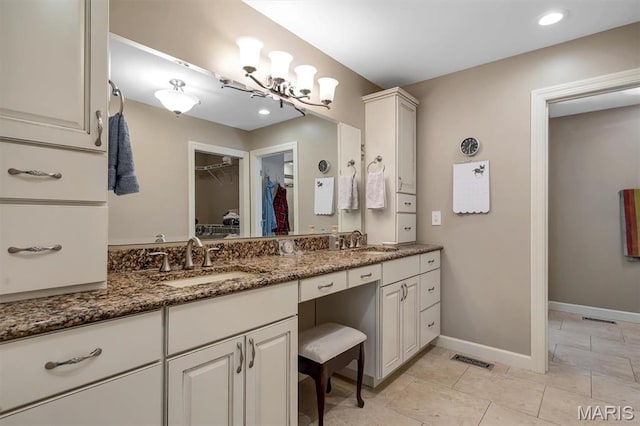 full bath with baseboards, vanity, a spacious closet, recessed lighting, and a chandelier