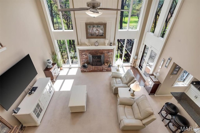 living room featuring a towering ceiling, a fireplace, and a ceiling fan