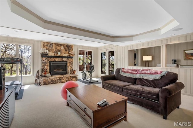 living area featuring a raised ceiling, light colored carpet, crown molding, a fireplace, and plenty of natural light