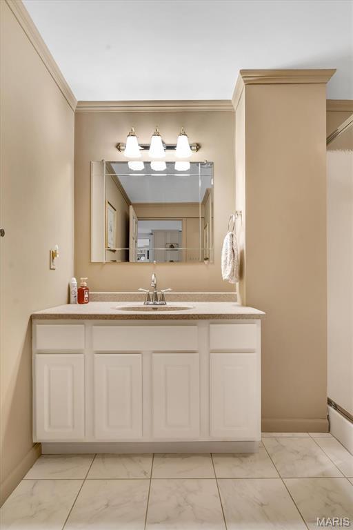 bathroom featuring marble look tiles, vanity, and ornamental molding