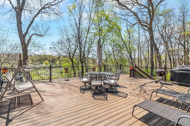 wooden terrace with outdoor dining area and a grill