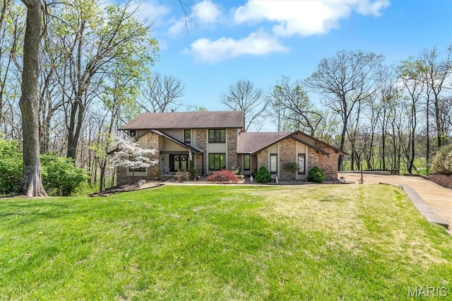 view of front of property featuring driveway, stone siding, a front lawn, and brick siding