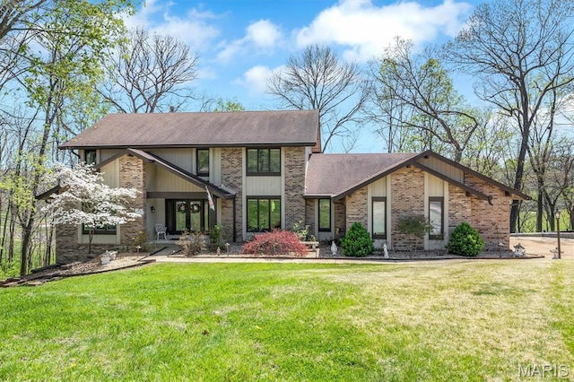 view of front of property featuring brick siding, a shingled roof, and a front yard