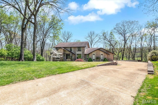 view of front facade featuring driveway, a front lawn, brick siding, and stone siding