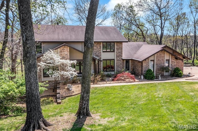 mid-century inspired home with roof with shingles, a front yard, and brick siding