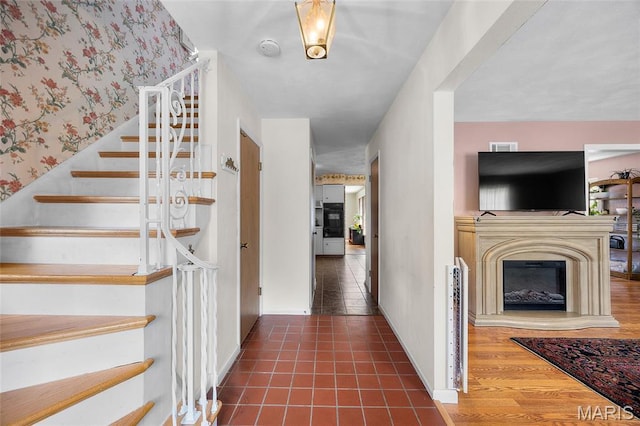 6623 Neosho St, Saint Louis, MO 63109 - stairs with baseboards, wallpapered walls, a fireplace with raised hearth, and tile patterned flooring