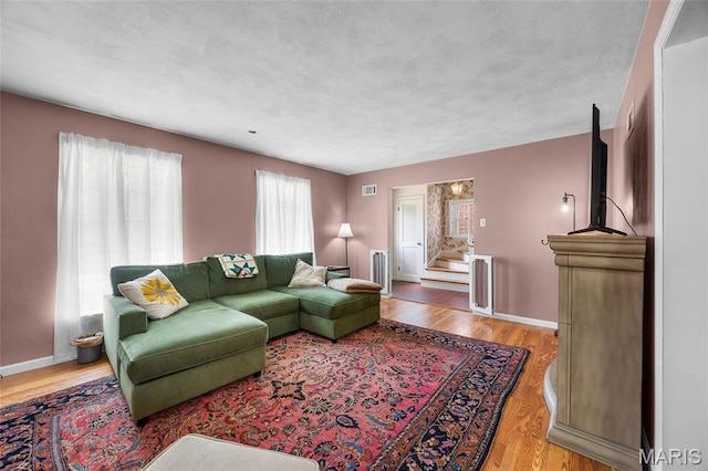 6623 Neosho St, Saint Louis, MO 63109 - living room featuring baseboards, light wood-type flooring, radiator, and stairway