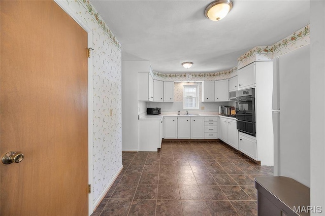 6623 Neosho St, Saint Louis, MO 63109 - kitchen with wallpapered walls, oven, a warming drawer, white cabinetry, and light countertops