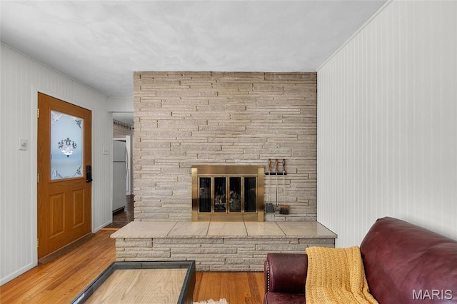 6623 Neosho St, Saint Louis, MO 63109 - living room featuring a stone fireplace, wood finished floors, crown molding, and wooden walls