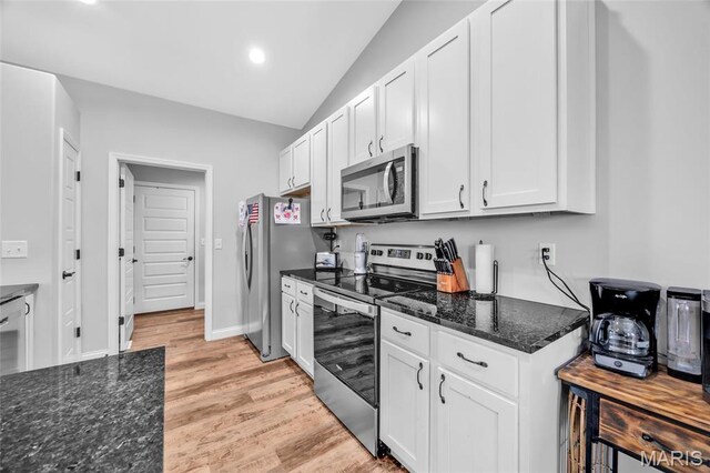1103 Baseball Dr, Foristell, MO 63348 - kitchen featuring appliances with stainless steel finishes, lofted ceiling, light wood-type flooring, dark stone counters, and white cabinets