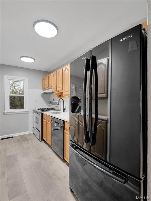 3100 Edgemont Ct, Saint Ann, MO 63074 - kitchen with black appliances, light countertops, light brown cabinets, under cabinet range hood, and a sink