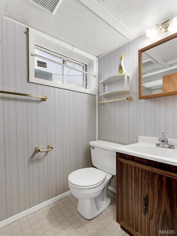 3100 Edgemont Ct, Saint Ann, MO 63074 - bathroom with toilet, vanity, a textured ceiling, wallpapered walls, and baseboards