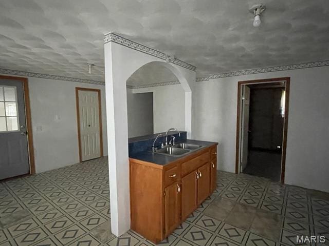 515 S Main St, Fredericktown, MO 63645 - kitchen featuring a sink, arched walkways, dark countertops, brown cabinetry, and light tile patterned floors