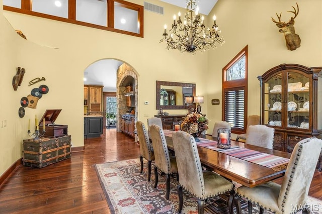 16480 Walnut Rail Rd, Chesterfield, MO 63005 - dining space featuring arched walkways, dark wood finished floors, a high ceiling, baseboards, and a chandelier