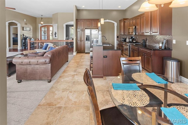7048 Alston Ct, Edwardsville, IL 62025 - kitchen with appliances with stainless steel finishes, arched walkways, a sink, decorative backsplash, and a kitchen island with sink