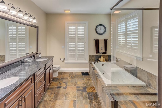 7048 Alston Ct, Edwardsville, IL 62025 - bathroom featuring a garden tub, toilet, stone finish flooring, double vanity, and baseboards