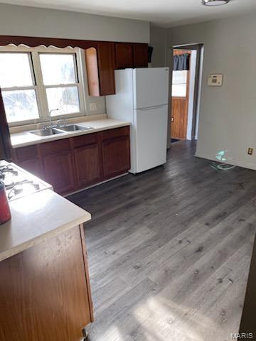 110 Barto Dr, Saint Louis, MO 63135 - kitchen with freestanding refrigerator, a sink, light countertops, wood finished floors, and brown cabinets