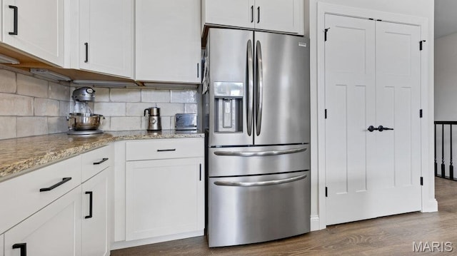 kitchen with stainless steel refrigerator with ice dispenser, tasteful backsplash, dark wood-style flooring, light stone countertops, and white cabinets