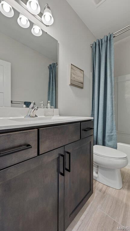 full bathroom featuring toilet, vanity, and shower / tub combo with curtain