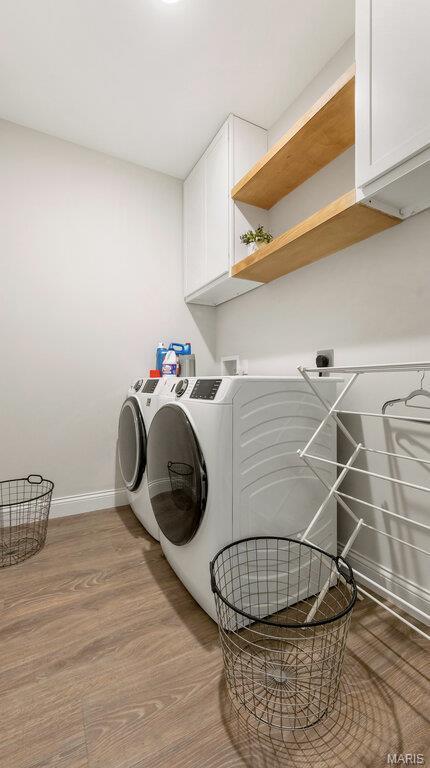 laundry room with washer and dryer, cabinet space, baseboards, and wood finished floors