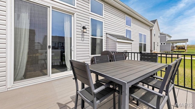 wooden terrace with outdoor dining area and a yard