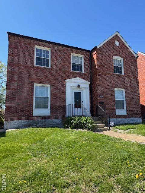 view of front of property featuring brick siding and a front lawn