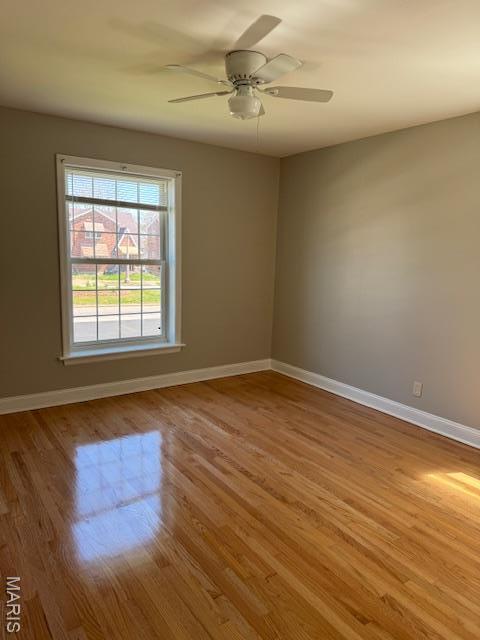 empty room with wood finished floors, baseboards, and ceiling fan