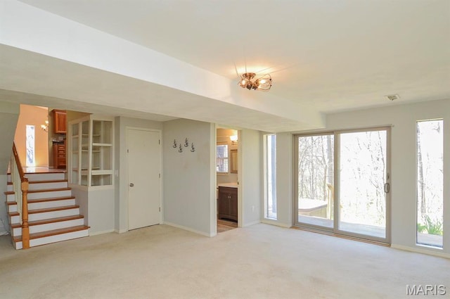 unfurnished living room featuring light colored carpet, stairs, and baseboards