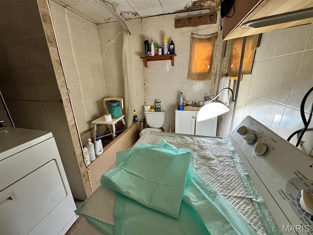 laundry room featuring tile walls and washer / dryer