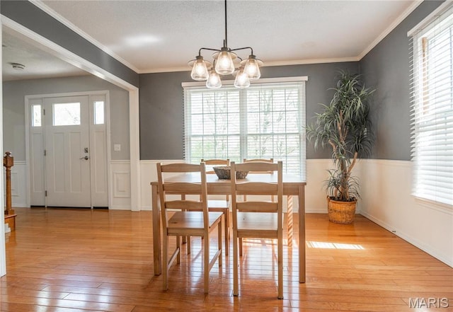 16747 Chalk Bluff Trl, Dexter, MO 63841 - dining room featuring light wood-style floors, wainscoting, a chandelier, healthy amount of natural light, and crown molding