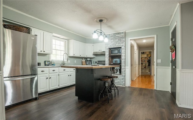 16747 Chalk Bluff Trl, Dexter, MO 63841 - kitchen featuring freestanding refrigerator, under cabinet range hood, a textured ceiling, white cabinetry, and crown molding
