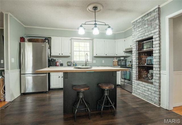 16747 Chalk Bluff Trl, Dexter, MO 63841 - kitchen featuring appliances with stainless steel finishes, white cabinets, crown molding, pendant lighting, and dark wood-style flooring