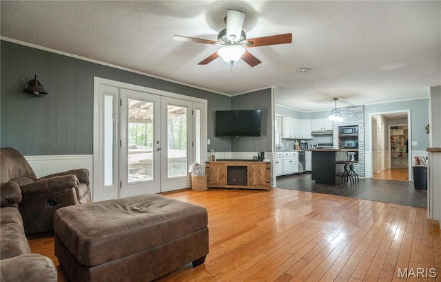 16747 Chalk Bluff Trl, Dexter, MO 63841 - living area with ornamental molding, french doors, light wood finished floors, a ceiling fan, and wainscoting