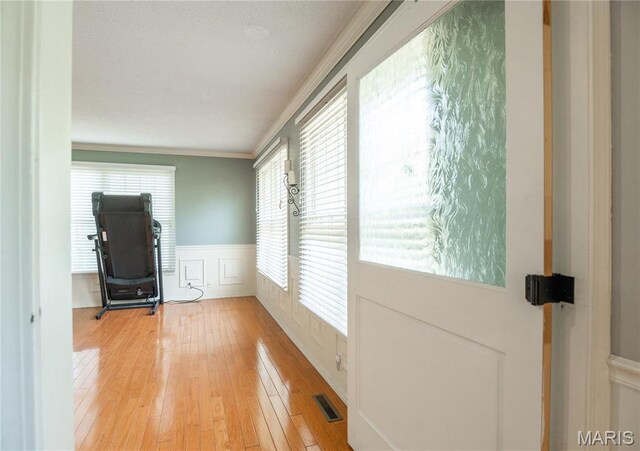 16747 Chalk Bluff Trl, Dexter, MO 63841 - doorway to outside with wainscoting, ornamental molding, light wood-type flooring, and a decorative wall