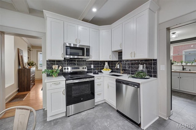kitchen with stainless steel appliances, a sink, light countertops, and white cabinetry