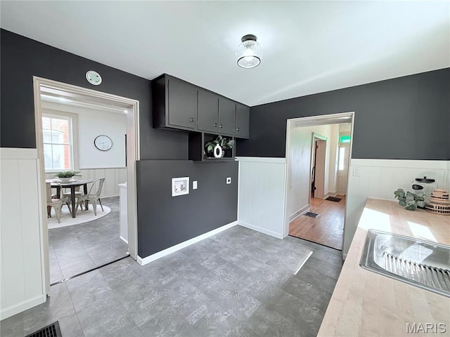 kitchen featuring wainscoting, light countertops, a sink, and a decorative wall