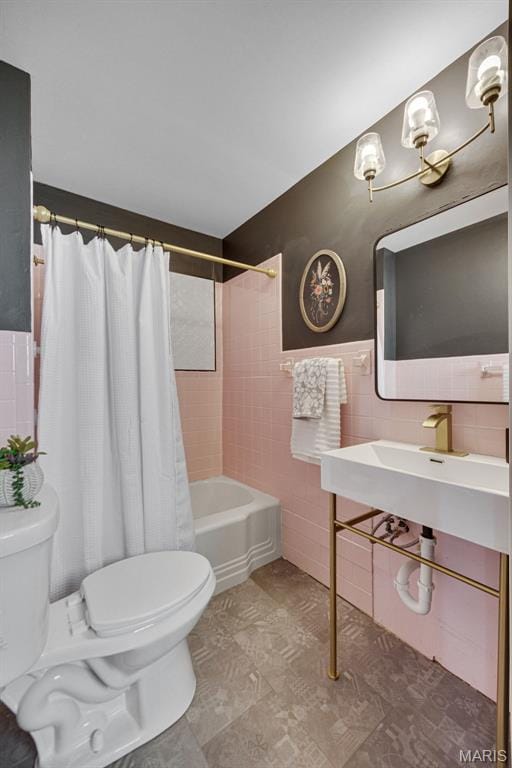bathroom featuring tile walls, toilet, shower / bath combo, and a sink