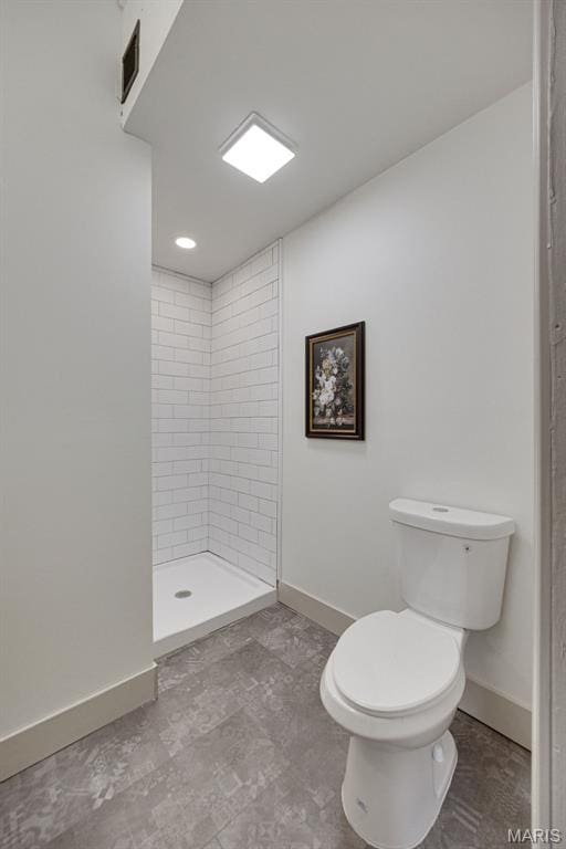 bathroom with baseboards, toilet, and a stall shower