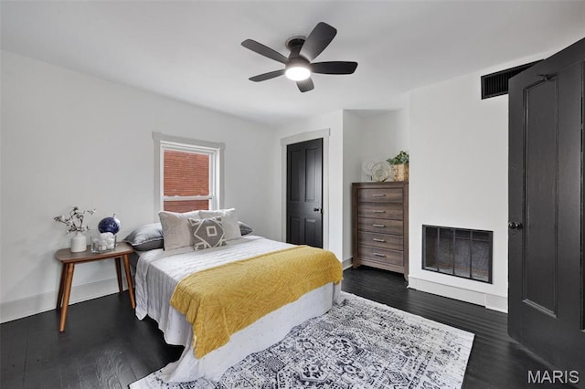 bedroom with dark wood-style floors, a fireplace, baseboards, and ceiling fan