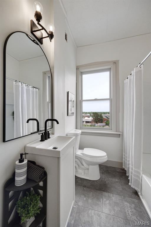 full bath featuring toilet, vanity, and baseboards