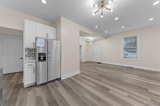 236 Georgia Ave, Saint Louis, MO 63135 - kitchen with a chandelier, stainless steel fridge, light wood-style floors, white cabinets, and baseboards
