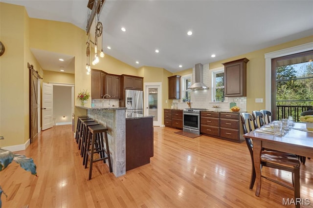 409 Pawnee Dr, Irondale, MO 63648 - kitchen featuring stainless steel appliances, vaulted ceiling, wall chimney range hood, decorative backsplash, and a peninsula