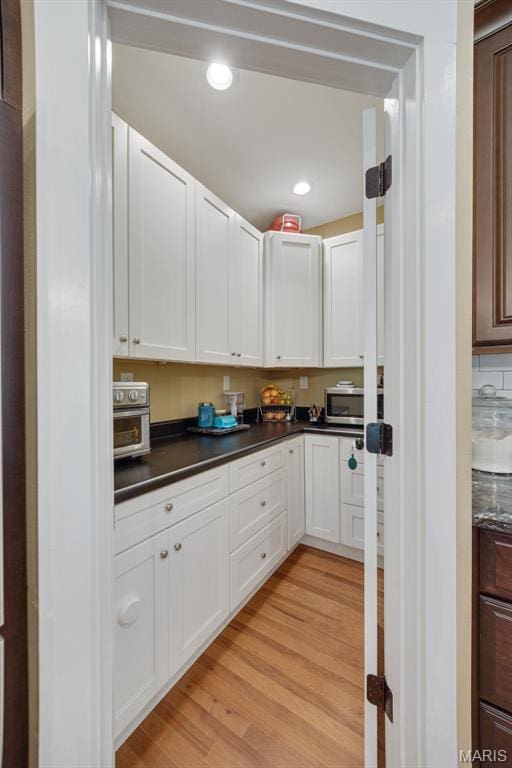 409 Pawnee Dr, Irondale, MO 63648 - kitchen featuring dark countertops, light wood-style floors, white cabinetry, recessed lighting, and stainless steel microwave