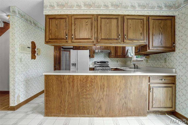 14 Sierra Dr, Glen Carbon, IL 62034 - kitchen with gas range, white refrigerator with ice dispenser, a peninsula, light countertops, and brown cabinets