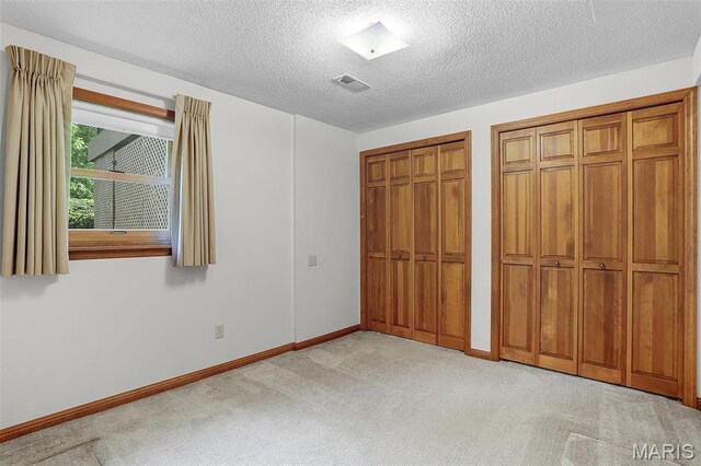 14 Sierra Dr, Glen Carbon, IL 62034 - unfurnished bedroom featuring two closets, carpet, a textured ceiling, and baseboards