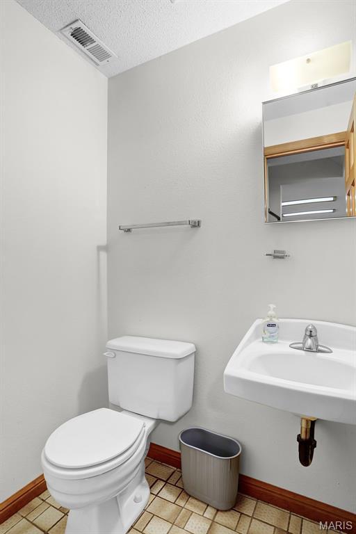14 Sierra Dr, Glen Carbon, IL 62034 - half bath featuring toilet, a textured ceiling, baseboards, and a sink