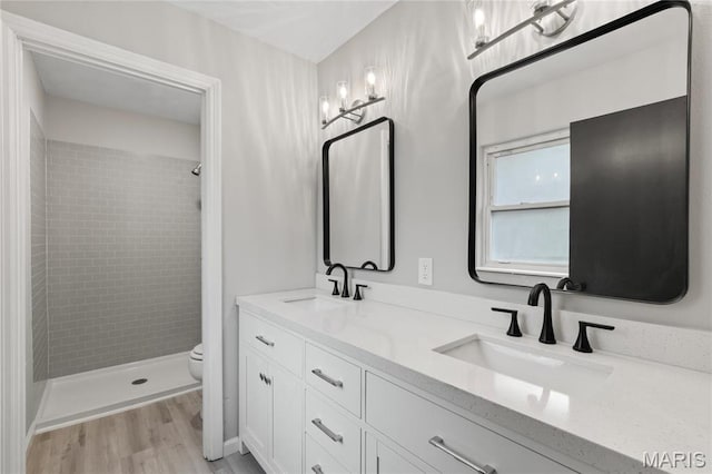 11735 Old Halls Ferry Rd, Florissant, MO 63033 - bathroom with toilet, double vanity, tiled shower, and wood finished floors