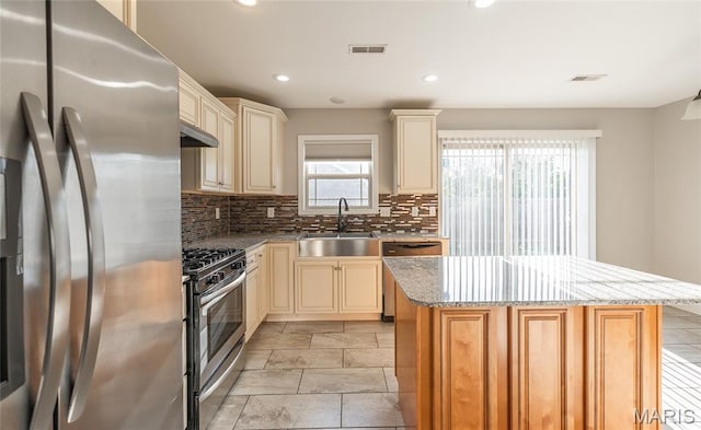 11175 Lexington Ln, Rolla, MO 65401 - kitchen featuring appliances with stainless steel finishes, a sink, cream cabinets, backsplash, and light stone counters