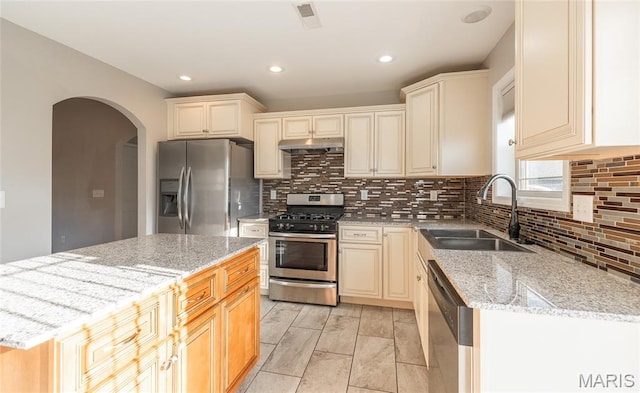 11175 Lexington Ln, Rolla, MO 65401 - kitchen featuring a sink, stainless steel appliances, arched walkways, under cabinet range hood, and light stone countertops