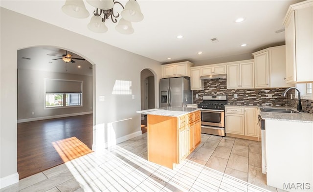 11175 Lexington Ln, Rolla, MO 65401 - kitchen with stainless steel appliances, arched walkways, a sink, decorative backsplash, and under cabinet range hood